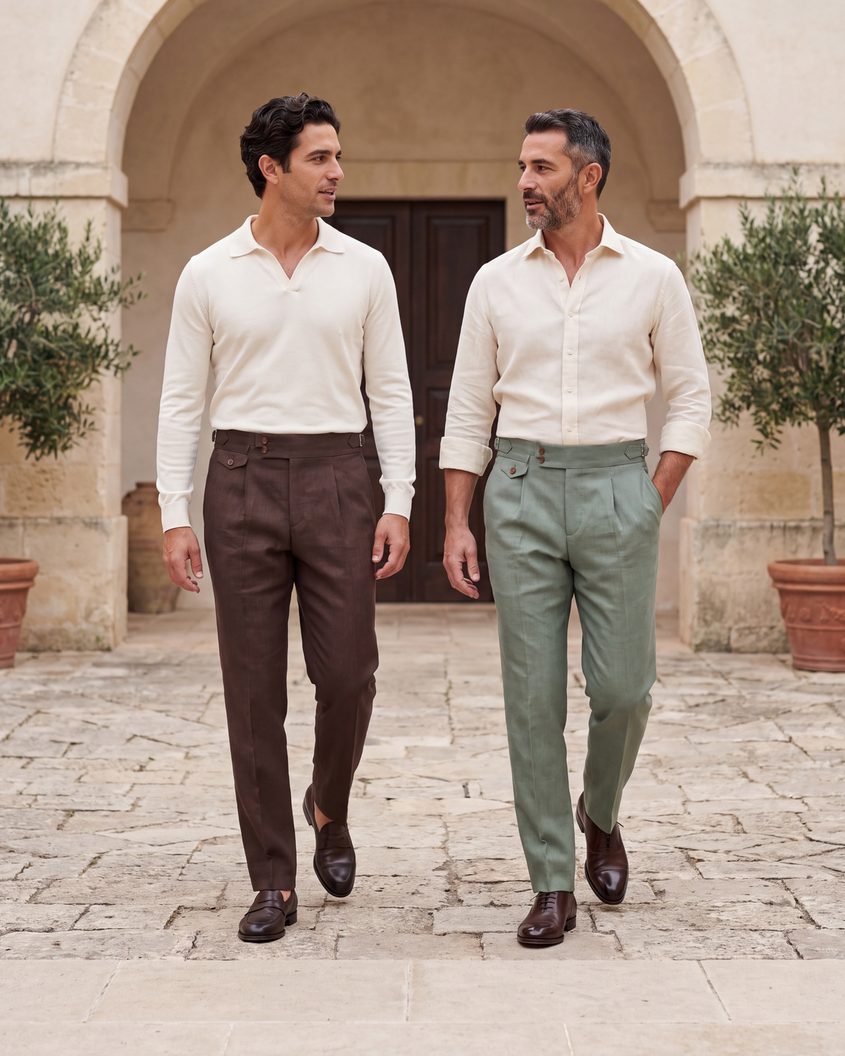 Two men in Squalo Gurkha pants, brown and sage, walking through a stone courtyard